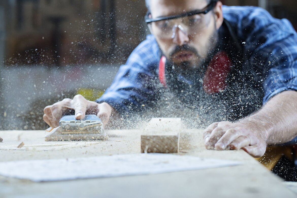 Handwerker bearbeitet Holz mit einem Elektrohobel