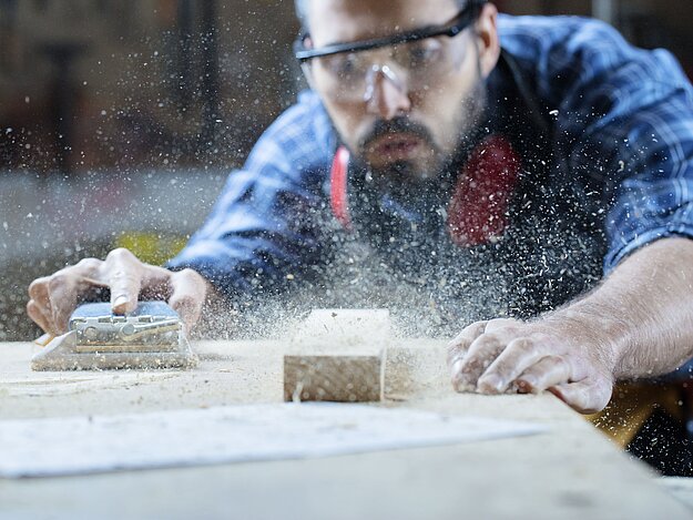 Handwerker bearbeitet Holz mit einem Elektrohobel