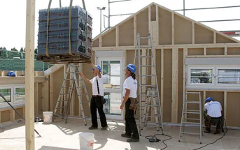 Arbeiter beim Aufbau eines Fertighauses mit Holzständerkonstruktion